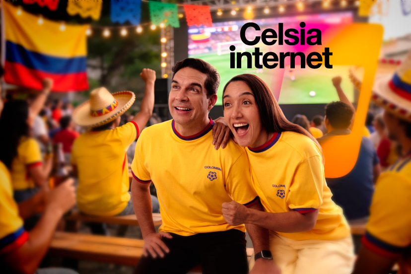 Pareja de hombre y mujer con camiseta amarilla alusiva a Colombia viendo un partido de futbol